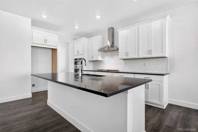 a kitchen with kitchen island granite countertop a sink and a stove