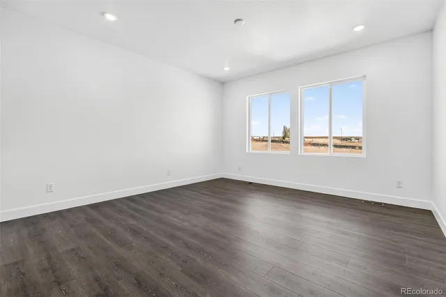 an empty room with wooden floor and window