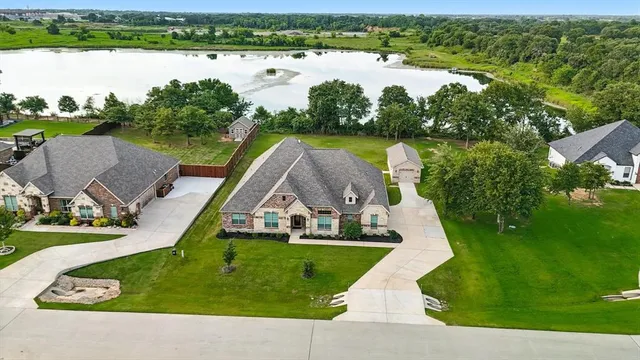 an aerial view of a house with green landscape and water view