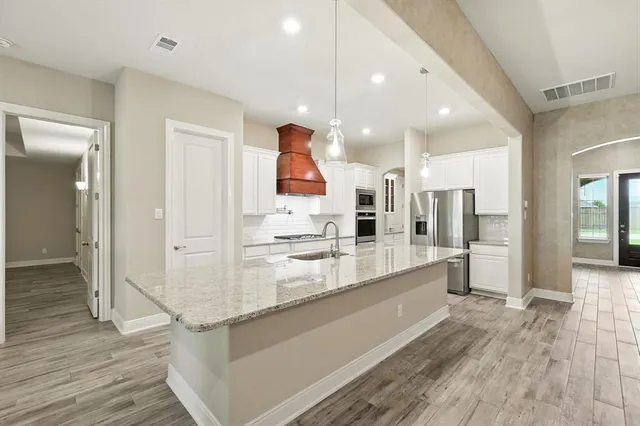 a large white kitchen with a large counter top and stainless steel appliances