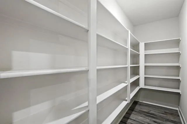 a large kitchen with stainless steel appliances kitchen island granite countertop a large stove a sink dishwasher and white cabinets with wooden floor