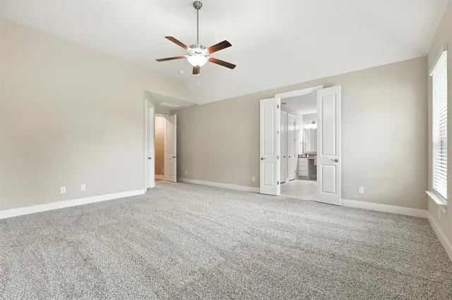an empty room with windows and ceiling fan