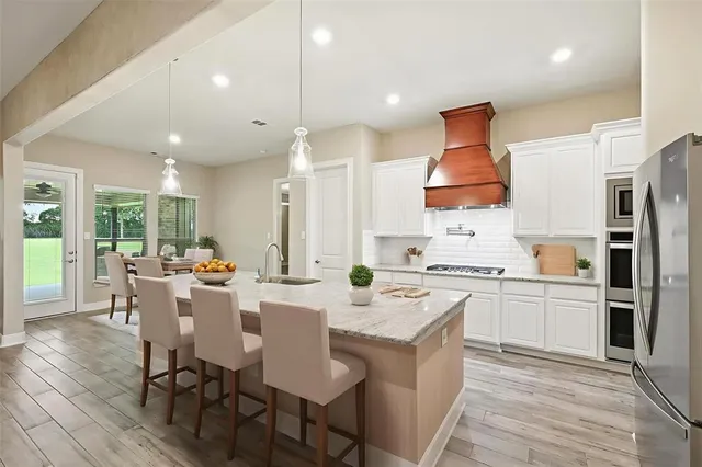 a kitchen with stainless steel appliances a dining table chairs stove refrigerator and cabinets