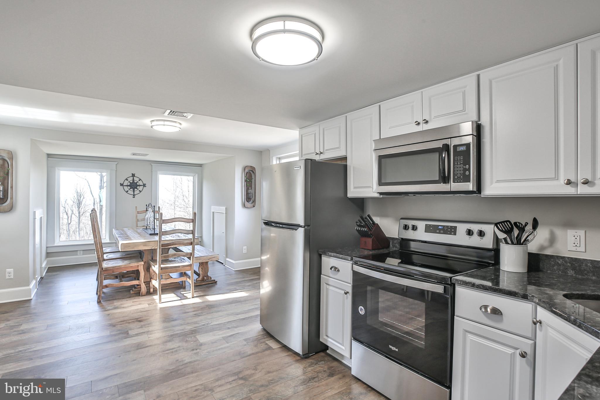 17345 Raven Rocks Road Bluemont, VA 20135 - Photo 78 of 99 a kitchen with stainless steel appliances granite countertop a stove top oven a sink dishwasher a dining table and chairs with wooden floor