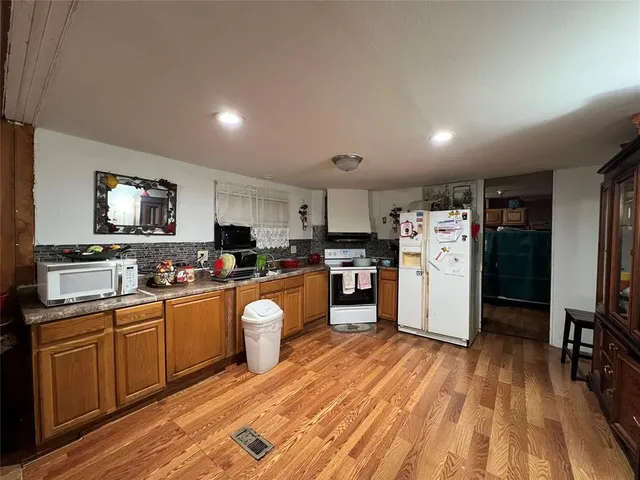 a kitchen with stainless steel appliances a refrigerator a stove top oven a sink dishwasher and white cabinets with wooden floor