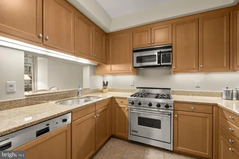 a kitchen with granite countertop white cabinets and stainless steel appliances