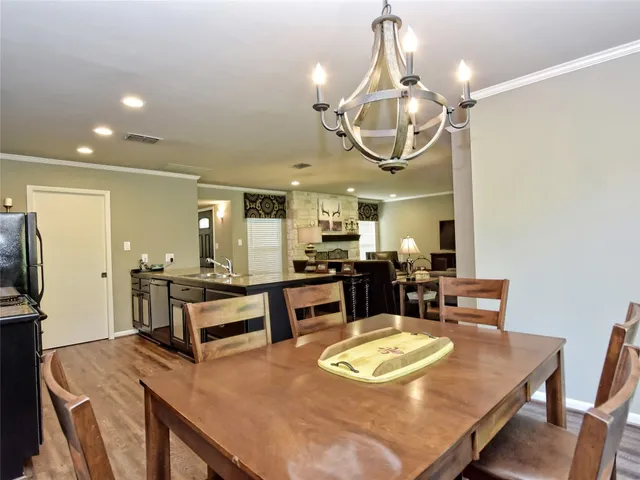 a kitchen with stainless steel appliances granite countertop a stove a refrigerator a oven a dining table and chairs with wooden floor