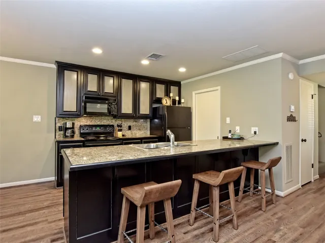 a kitchen with stainless steel appliances granite countertop a table chairs sink refrigerator and microwave