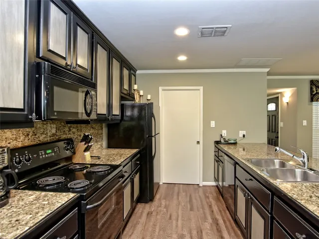 a kitchen with stainless steel appliances granite countertop a stove a sink dishwasher a refrigerator and cabinets with wooden floor