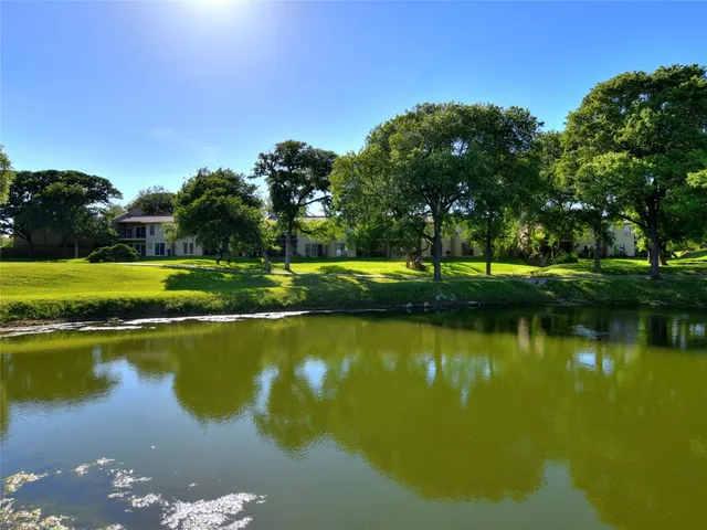 a view of a lake with a yard and large trees