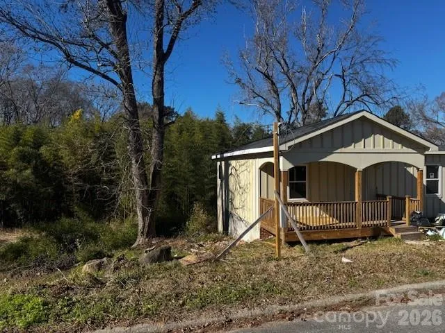a view of a small house with a yard and large tree