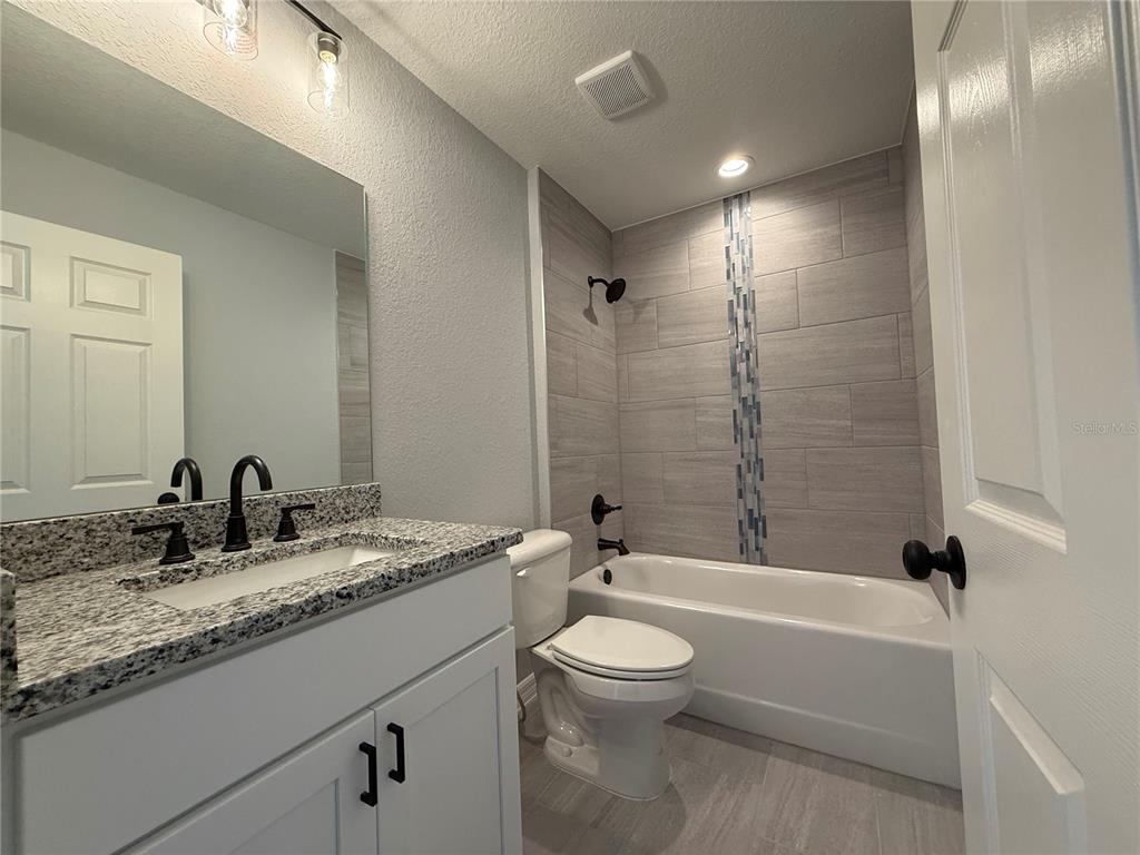 2460 Northwest Buena Vista Road Dunnellon, FL 34431 - Photo 12 of 14 a bathroom with a granite countertop sink a toilet and bathtub