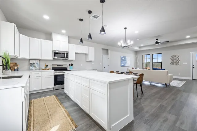 a large white kitchen with lots of counter space a sink appliances and cabinets