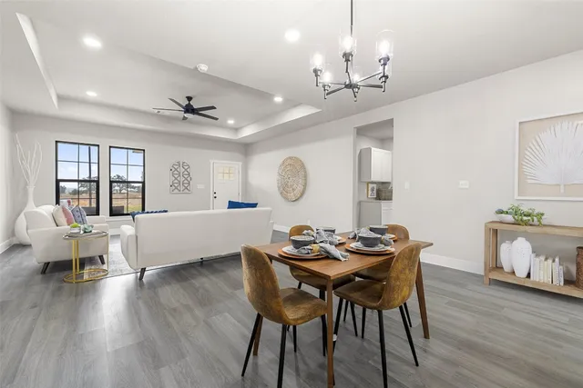 a dining room with wooden floor a chandelier a wooden table and chairs