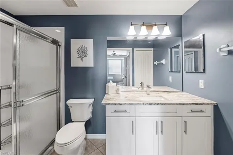 a bathroom with a granite countertop sink toilet a large mirror and a shower
