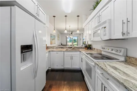 a kitchen with a sink dishwasher a refrigerator oven and white cabinets with wooden floor