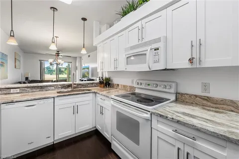 a kitchen with granite countertop white cabinets and white appliances