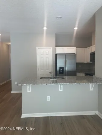 a view of a kitchen with stainless steel appliances wooden floor and living room