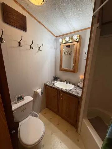 a bathroom with a granite countertop toilet sink and mirror