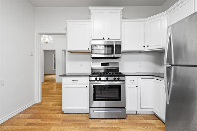 a kitchen with granite countertop a refrigerator stove a sink and dishwasher with wooden floor