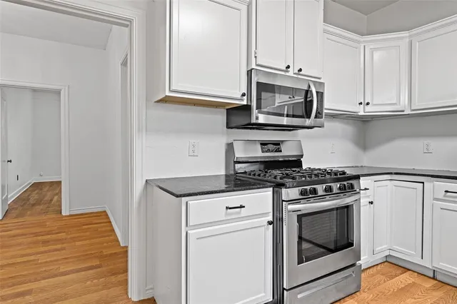 a kitchen with granite countertop white cabinets and window