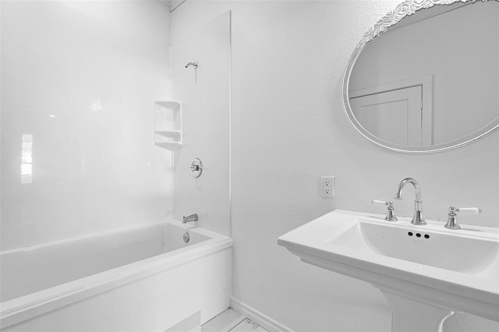 204 Jones Street Longview, TX 75602 - Photo 24 of 32 a white bath tub sitting next to a white sink and a mirror