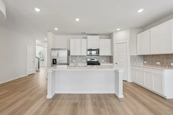 a kitchen with stainless steel appliances granite countertop a stove top oven a sink and white cabinets