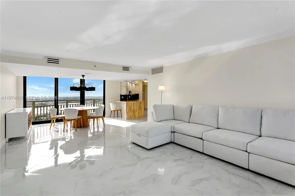 a living room with furniture white walls and kitchen view