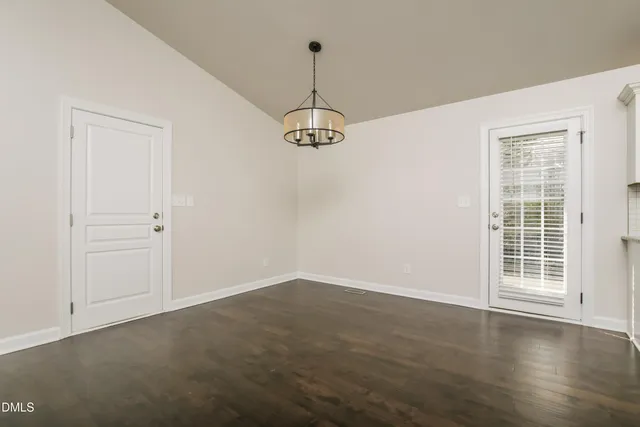 an empty room with wooden floor closet and windows