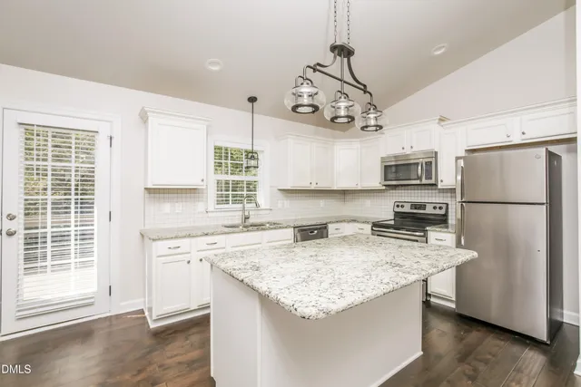 a kitchen with stainless steel appliances granite countertop a sink a stove a refrigerator cabinets and a window