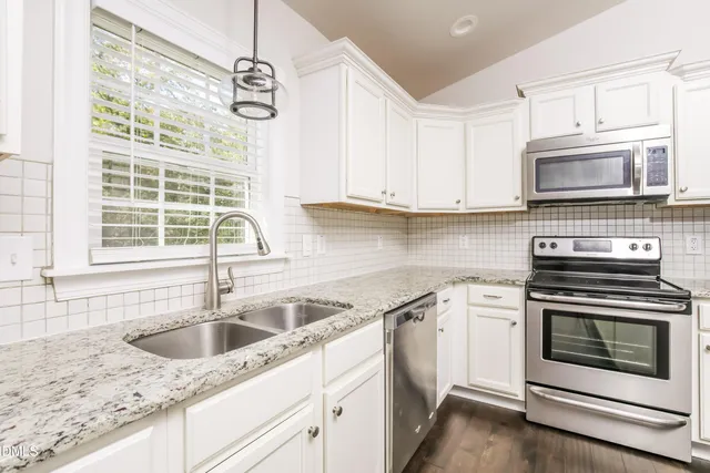 a kitchen with granite countertop a sink stainless steel appliances and cabinets