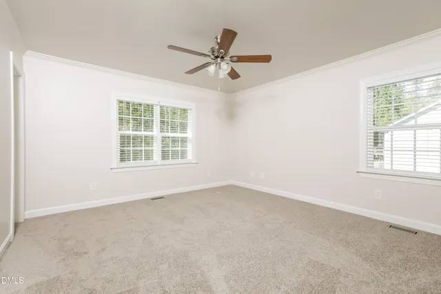 an empty room with windows and fan