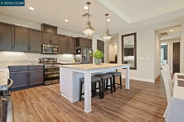 a kitchen with kitchen island granite countertop a sink wooden cabinets and stainless steel appliances