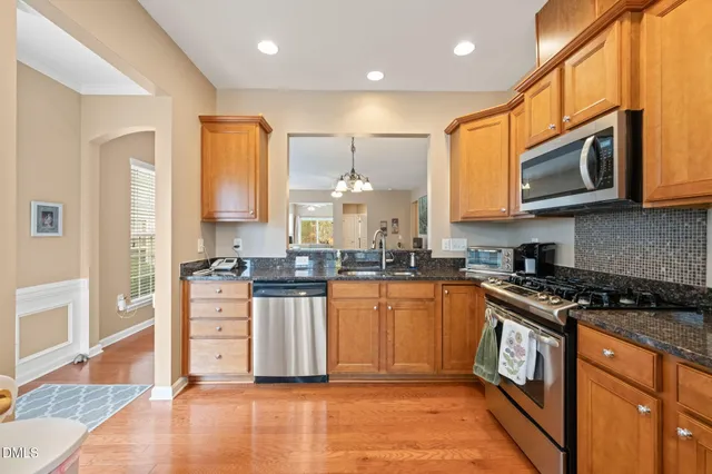 a kitchen with stainless steel appliances granite countertop a stove a sink and a microwave