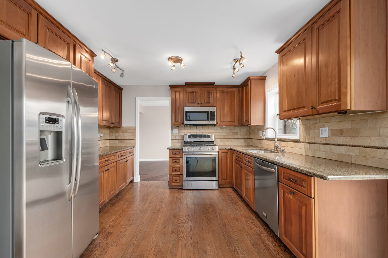 7804 Rohrer Drive Downers Grove, IL 60516 - Photo 8 of 28 a kitchen with stainless steel appliances granite countertop refrigerator a sink and wooden cabinets
