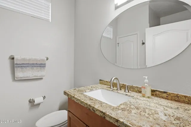 a bathroom with a granite countertop toilet sink and mirror