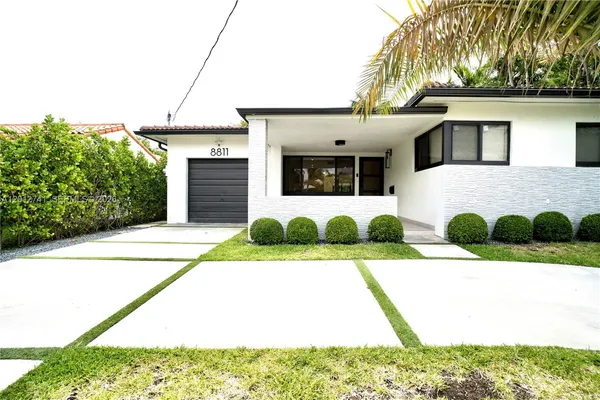a view of a white house with a yard and potted plants
