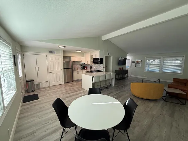 a living room with stainless steel appliances furniture a dining table and chairs