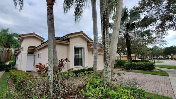 a view of a white house with a small yard and palm trees