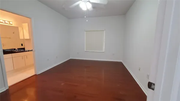 an empty room with windows and chandelier fan