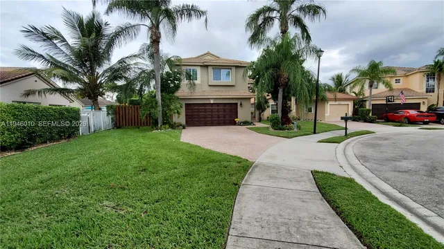 a view of a house with a yard and palm trees
