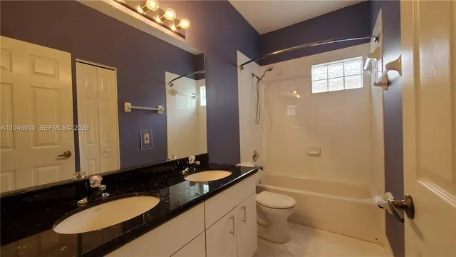 a bathroom with a granite countertop sink toilet a mirror and shower