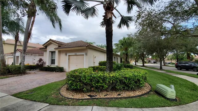 a view of a white house with a big yard and potted plants
