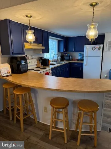 a kitchen with kitchen island a dining table chairs refrigerator and cabinets