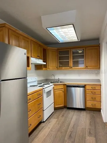 a kitchen with granite countertop stainless steel appliances a refrigerator and a stove top oven