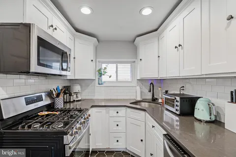 a kitchen with granite countertop stainless steel appliances a stove sink and cabinets