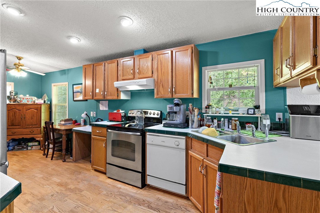 787 Lawrence Greene Road Deep Gap, NC 28618 - Photo 14 of 45 a kitchen with stainless steel appliances granite countertop a stove top oven a sink dishwasher and cabinets with wooden floor
