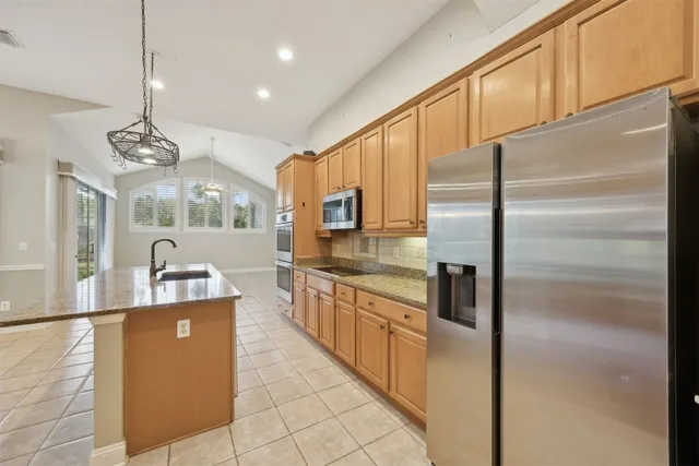 a kitchen with stainless steel appliances granite countertop a refrigerator a stove and a sink with cabinets