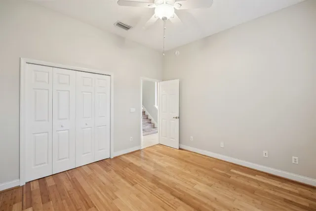 a view of empty room with wooden floor and ceiling fan