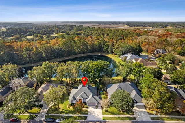 an aerial view of a house with a yard lake and mountain view in back